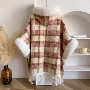 Detail eines pink-karierten Kapuzenponchos mit weißem Kunstpelzbesatz und langen Fransen