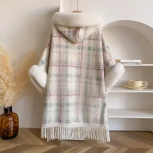 Details des karierten Kapuzenponchos mit luxuriösem Kunstpelzbesatz und Fransen