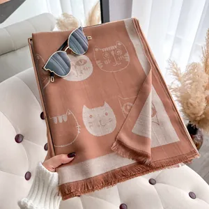 Detail of tencel cotton scarf showing white cat prints and fine fringe tassels on rust fabric