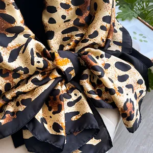 Detailed close-up of leopard print silk scarf with smooth texture and black border