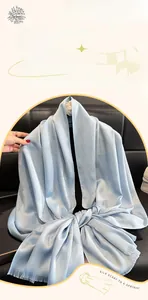 Detail of light blue silk scarf featuring shimmering silver texture and fine fringe edges