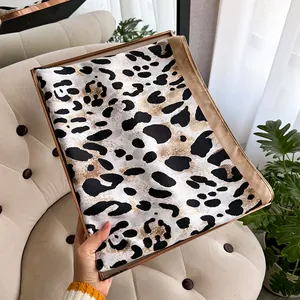 Close-up of lightweight leopard print silk scarf with luxury champagne gold satin edges