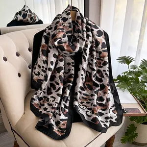 Close-up of elegant leopard print silk scarf with black piping on a beige chair
