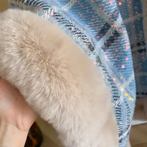 Gros plan du tweed à paillettes et du grand col en fausse fourrure d'une cape d'hiver femme