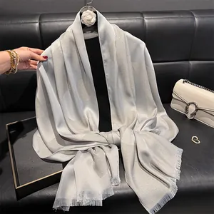 Detail of silver silk shawl featuring shiny circular patterns and delicate fringe trim
