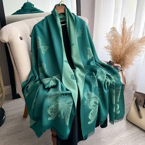 Écharpe élégante en soie et coton avec motif papillon et franges sur une chaise beige