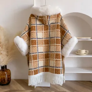 Detailstruktur des karierten Kapuzenponchos mit Kunstpelzbesatz und weißen Fransen