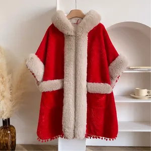 Gros plan détaillé d'une cape d'hiver rouge avec garniture en peluche et petits pompons