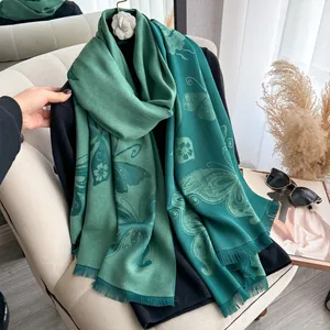 Vue détaillée d'une écharpe vert foncé avec motif papillon jacquard et bords à franges