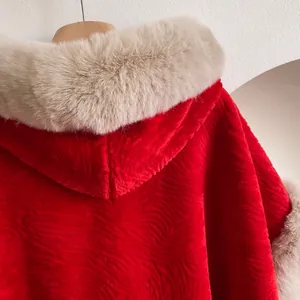 Détail de la cape rouge d'hiver montrant le tissu texturé et le col en fausse fourrure beige