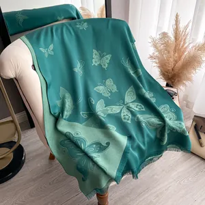 Détail du motif papillon sur une écharpe vert foncé aspect soie avec des franges