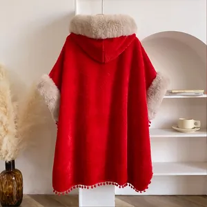 Détail de la cape rouge en polaire ondulée avec garniture en fausse fourrure et pompons