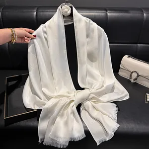 Detailed view of pearl white silk shawl featuring fine fringe and subtle shimmer texture