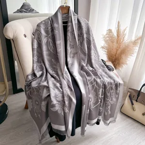 Close-up of high-quality grey jacquard scarf with leaf patterns and fringe detail