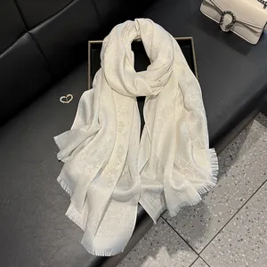 Detail of ivory faux silk scarf with elegant floral jacquard weave and delicate fringes