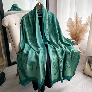 Detailed view of tencel cotton scarf showing green floral jacquard and tassel edges