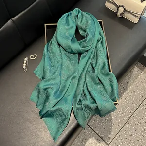 Elegant teal silk shawl with jacquard logo pattern and subtle metallic glitter details