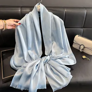 Detail of light blue silk scarf with subtle jacquard pattern and soft fringe edges