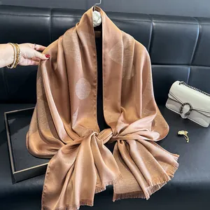 Detail of silk-like gold scarf with glitter geometric patterns and fringe edges