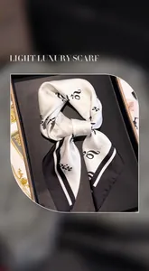 Detail of elegant black and white silk square scarf with cursive lettering in a gift box