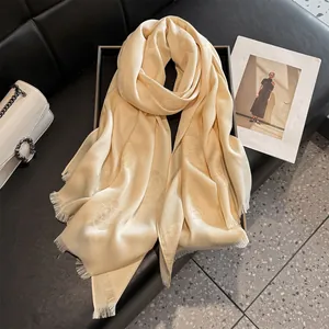Detailed macro view of champagne gold silk shawl with floral jacquard pattern and fringe