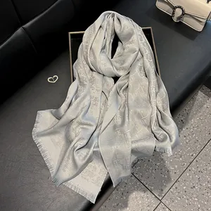 Detail of silver silk-blend scarf featuring jacquard texture and raw fringe edges