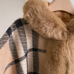 Detailaufnahme des karierten Wollponchos mit weichem Kunstfellkragen und dicker Textur