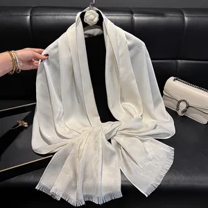 Detailed close-up of cream silk blend scarf featuring floral patterns and fringe edges