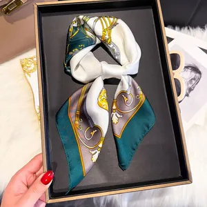 Green silk scarf with baroque pattern tied in a bow inside an elegant black gift box