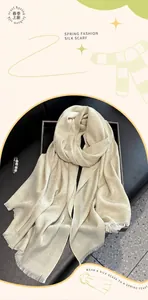 Detail of champagne gold silk scarf featuring floral texture and delicate short fringes