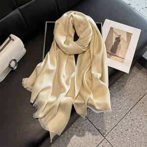 Macro detail of silk-like champagne floral scarf with frayed edges on leather display