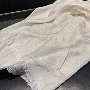 Detailed view of pearl white jacquard silk scarf with butterfly pattern and fine tassels