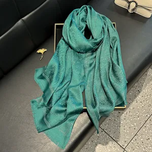 Detailed macro view of dark teal scarf with silver shimmer and floral jacquard patterns