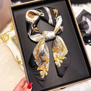Detailed view of a silk scarf with Baroque patterns on a black tray with luxury accessories