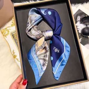 Detailed view of square silk scarf with paisley patterns in navy and blue on a tray