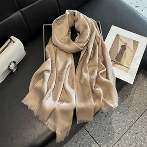 Detailed view of champagne silk scarf with camellia patterns and fringe edge details