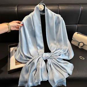 Detail of light blue silk scarf featuring butterfly patterns and soft fringe edges