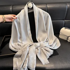 Detail of silver silk scarf with butterfly jacquard pattern and fine tassel edges