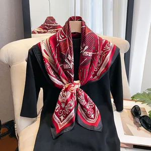Elegant red and black geometric silk scarf tied on a black knit top for a luxury style