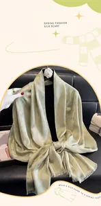 Primer plano de bufanda de seda verde menta con motivos de jacquard y detalles de borlas