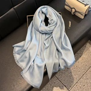 Elegant light blue silk scarf with silver shimmer and fringe on a black leather background