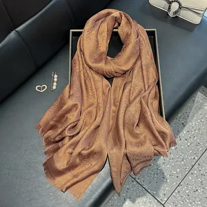 Detailed texture of brown silk shawl with gold glitter and leaf pattern fringe
