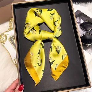 Detail of a floral silk scarf with yellow and pink lily patterns on a display tray