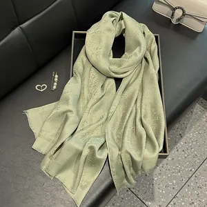 Sage green long silk scarf with floral jacquard texture displayed on a black tray