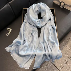 Detalle de bufanda azul claro con sutil patrón jacquard de leopardo y textura brillante
