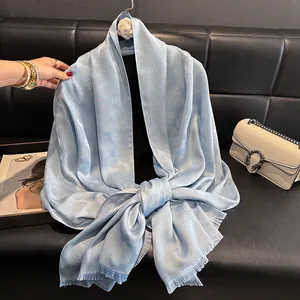 Detalle de chal de seda azul claro con jacquard floral y bordes de flecos finos y elegantes