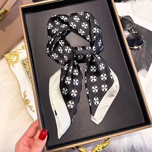 Detail shot of black and white floral silk scarf with glossy texture and geometric patterns