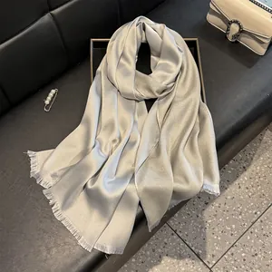 Detail of silver gray silk scarf featuring fringe edges and subtle pearlescent shimmer texture