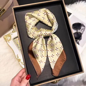 Close-up of champagne silk square scarf with vintage patterns on a black display tray