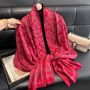 Detalle de chal de jacquard rojo con hilos metálicos brillantes y bordes de flecos